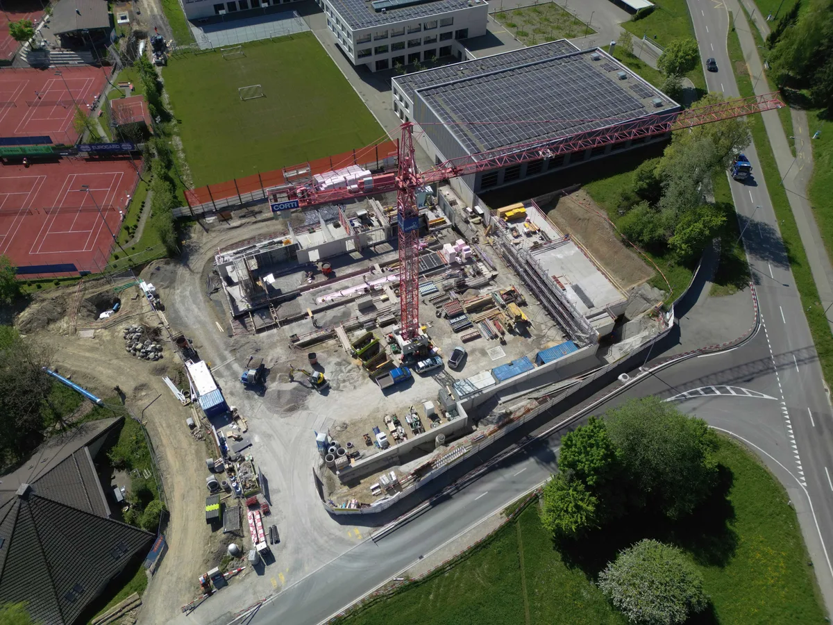 Das Bevölkerungsschutzgebäude auf der Looren-Anlage in Maur befindet sich im Bau. Im Bild oben links ist der Rasenplatz zu sehen, der nun umgebaut wird. Man sieht eine Baustelle und dahinter einen Fussballplatz von oben.